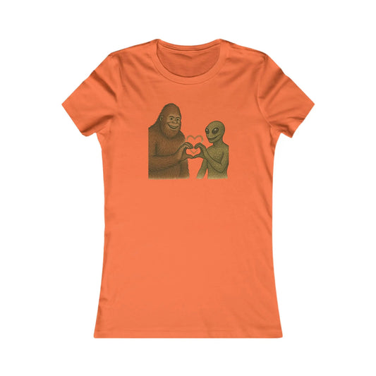 Orange t-shirt with a graphic of a bigfoot and an alien holding hands making a heart symbol on a white background