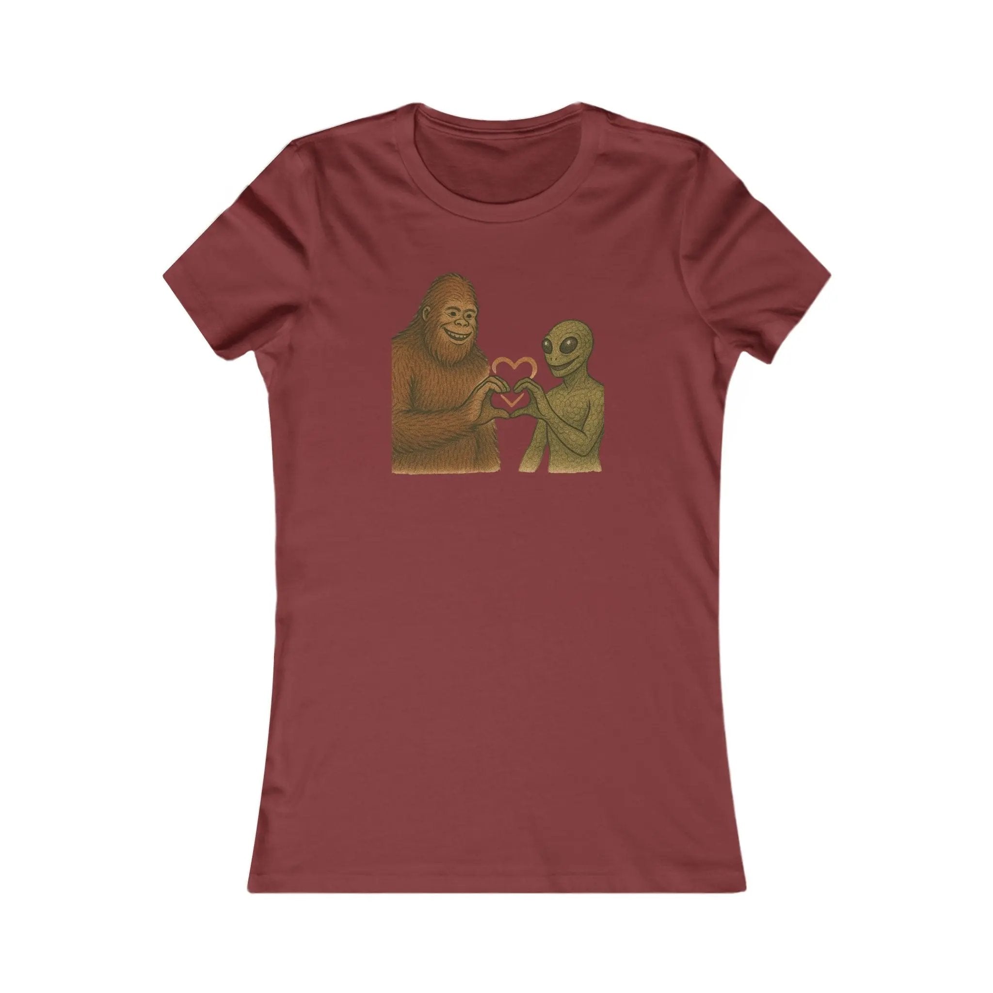 Maroon t-shirt with a graphic of a bigfoot and an alien holding hands making a heart symbol on a white background