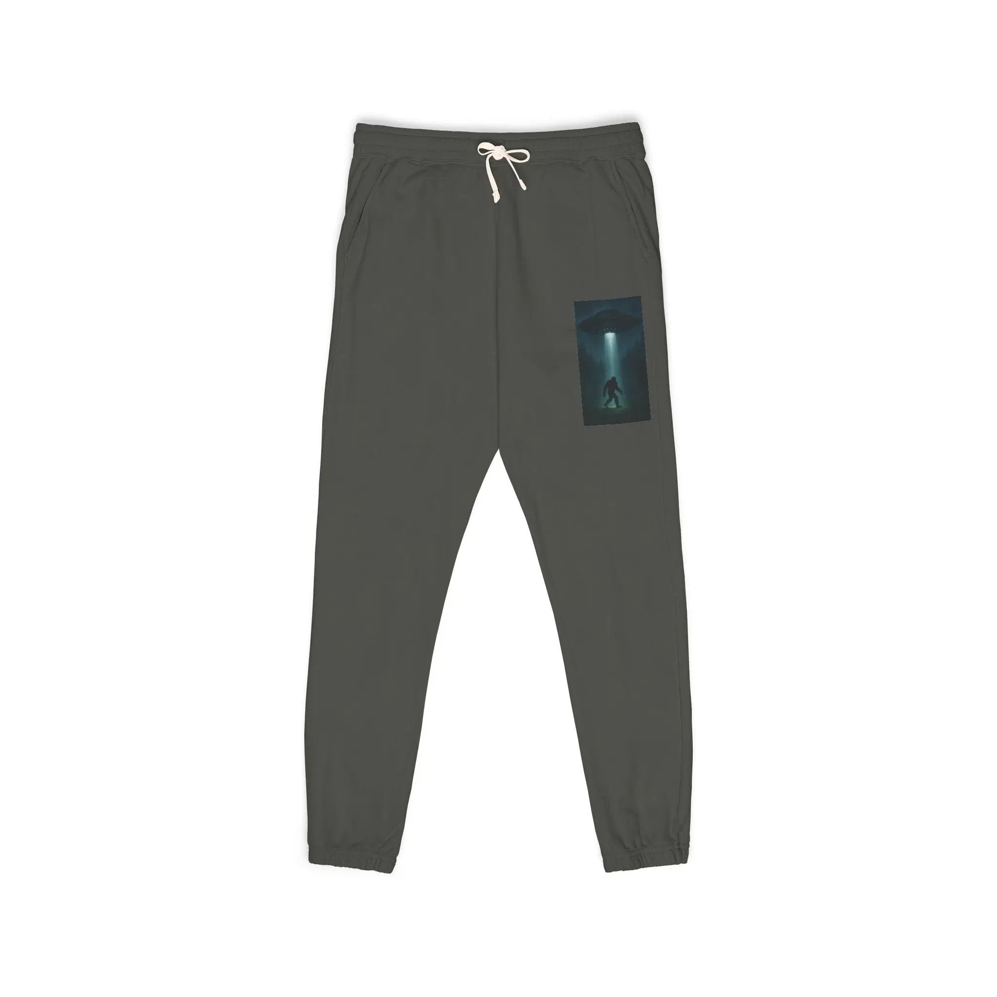 Dark gray sweatpants with a small graphic of a UFO with a beam of light on a bigfoot silhouette on the left leg on a white background