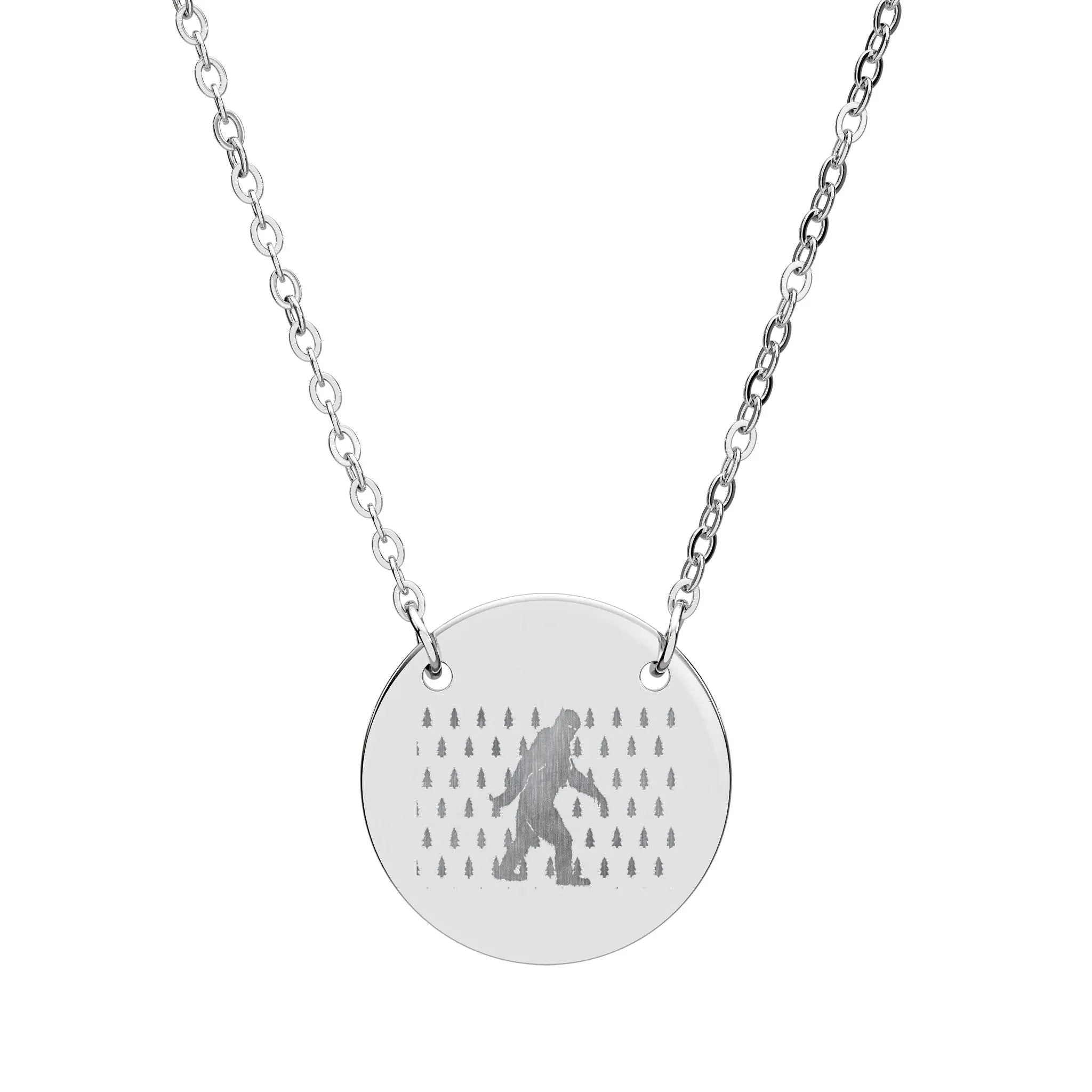 Silver necklace with a round pendant featuring a silhouette of bigfoot and tree pattern on a white background