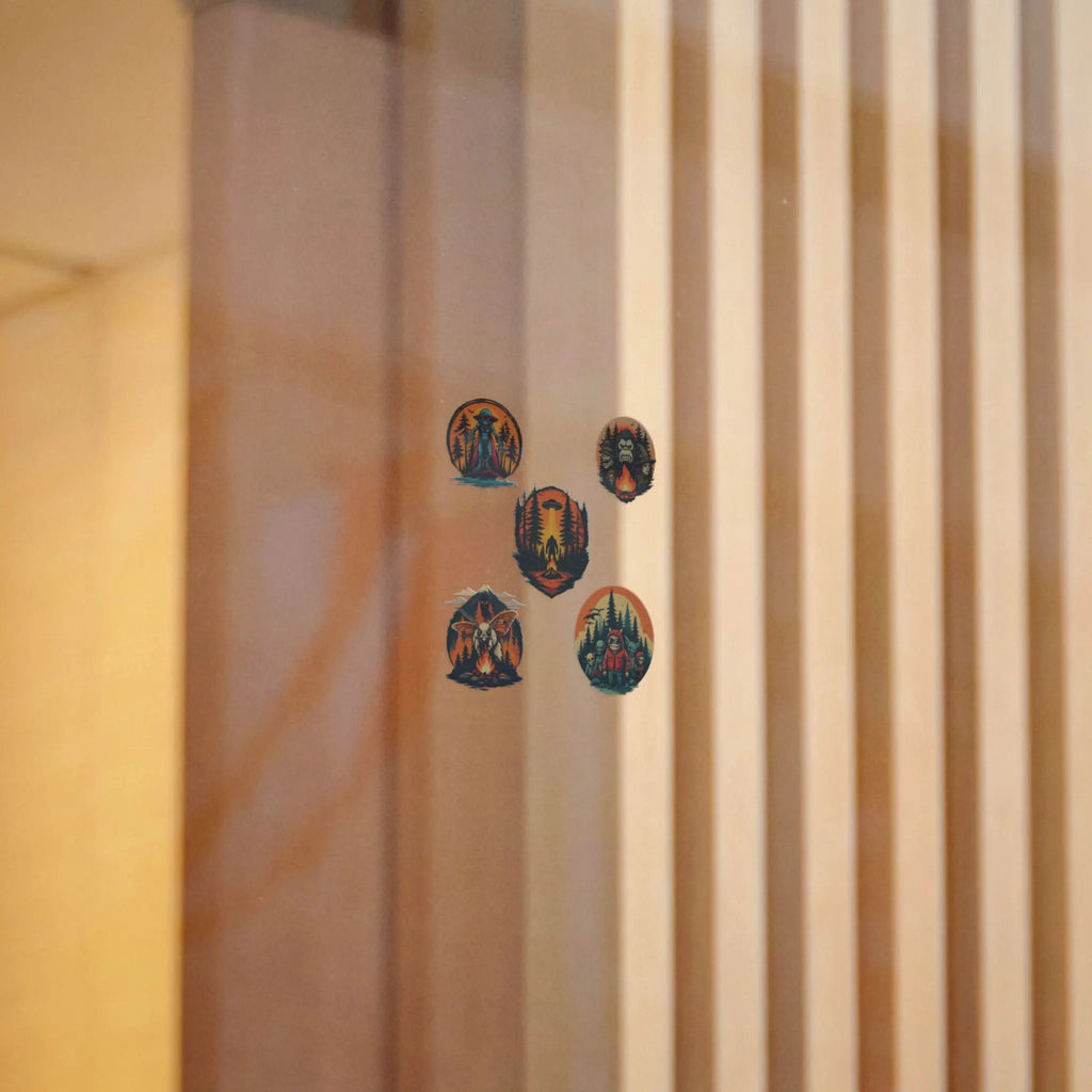 Five colorful circular stickers on a window with a beige curtain in the background