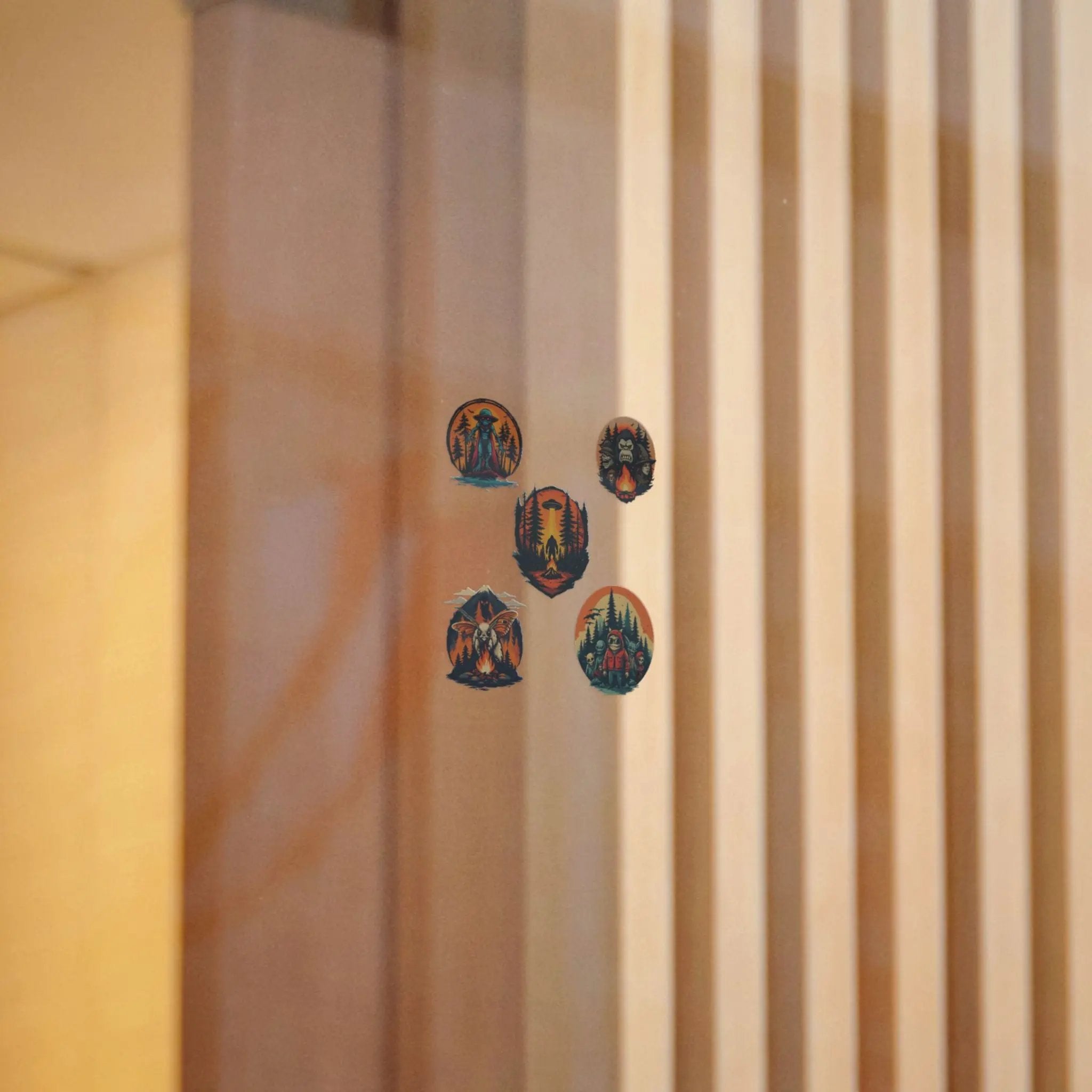 Five colorful circular stickers on a window with a beige curtain in the background