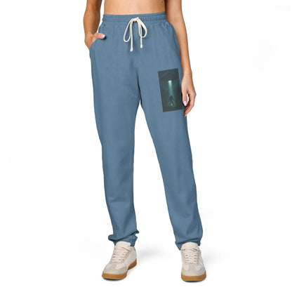 Blue sweatpants with a small graphic of a UFO with a beam of light on a bigfoot silhouette on the left leg on a white background