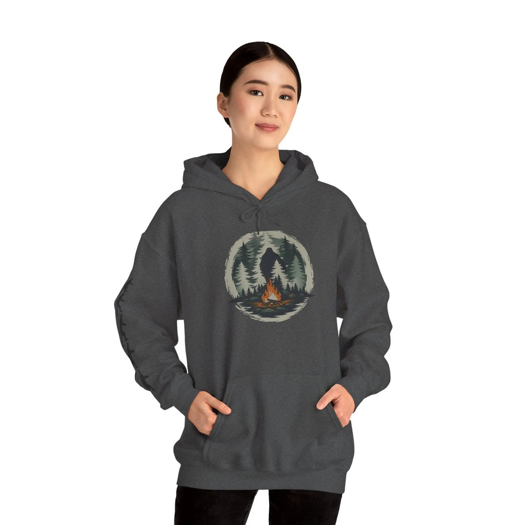 Person wearing a dark gray hoodie with a nature graphic and black bigfoot silhouettes on the right sleeve on a white background on a white background