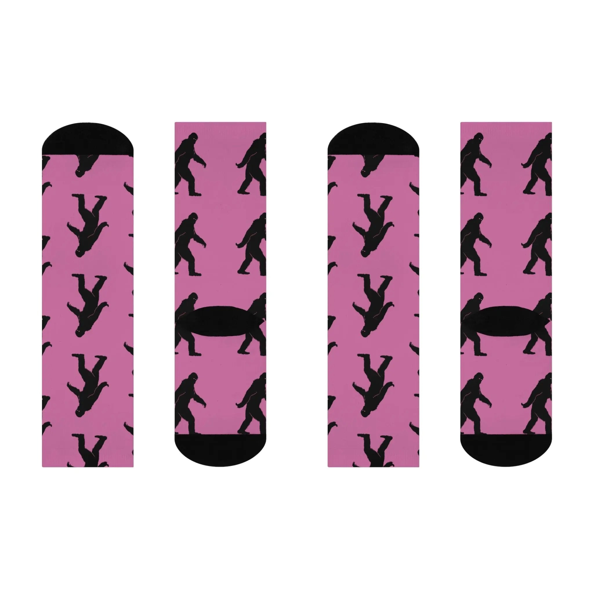Two pairs of pink socks with black bigfoot silhouette pattern on a white background