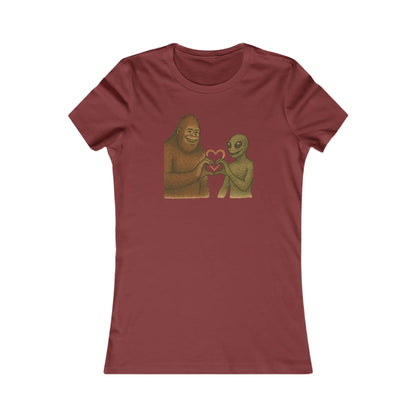 Maroon t-shirt with a graphic of a bigfoot and an alien holding hands making a heart symbol on a white background