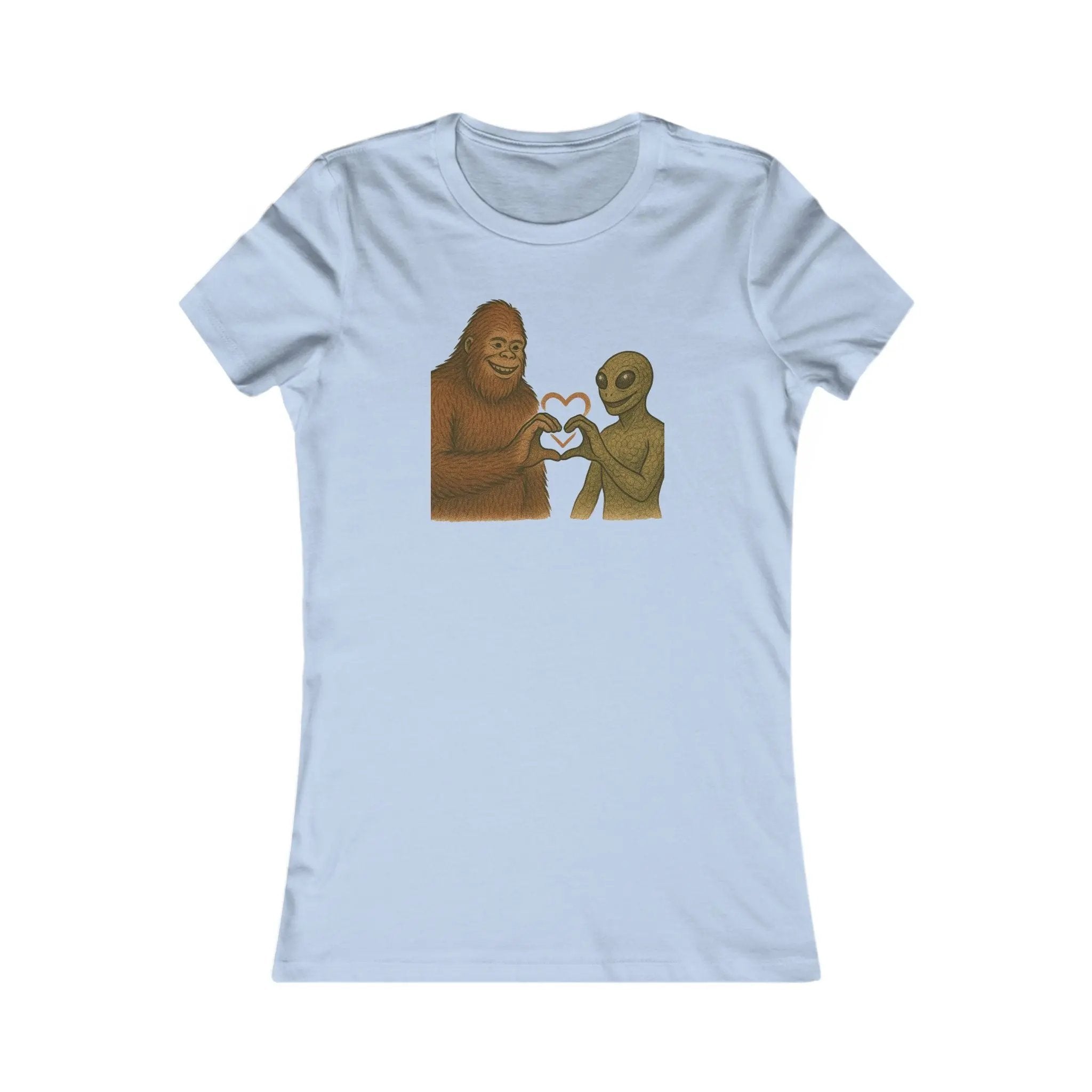 Light blue t-shirt with a graphic of a bigfoot and an alien holding hands making a heart symbol on a white background