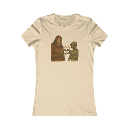 Beige t-shirt with a graphic of a bigfoot and an alien holding hands making a heart symbol on a white background