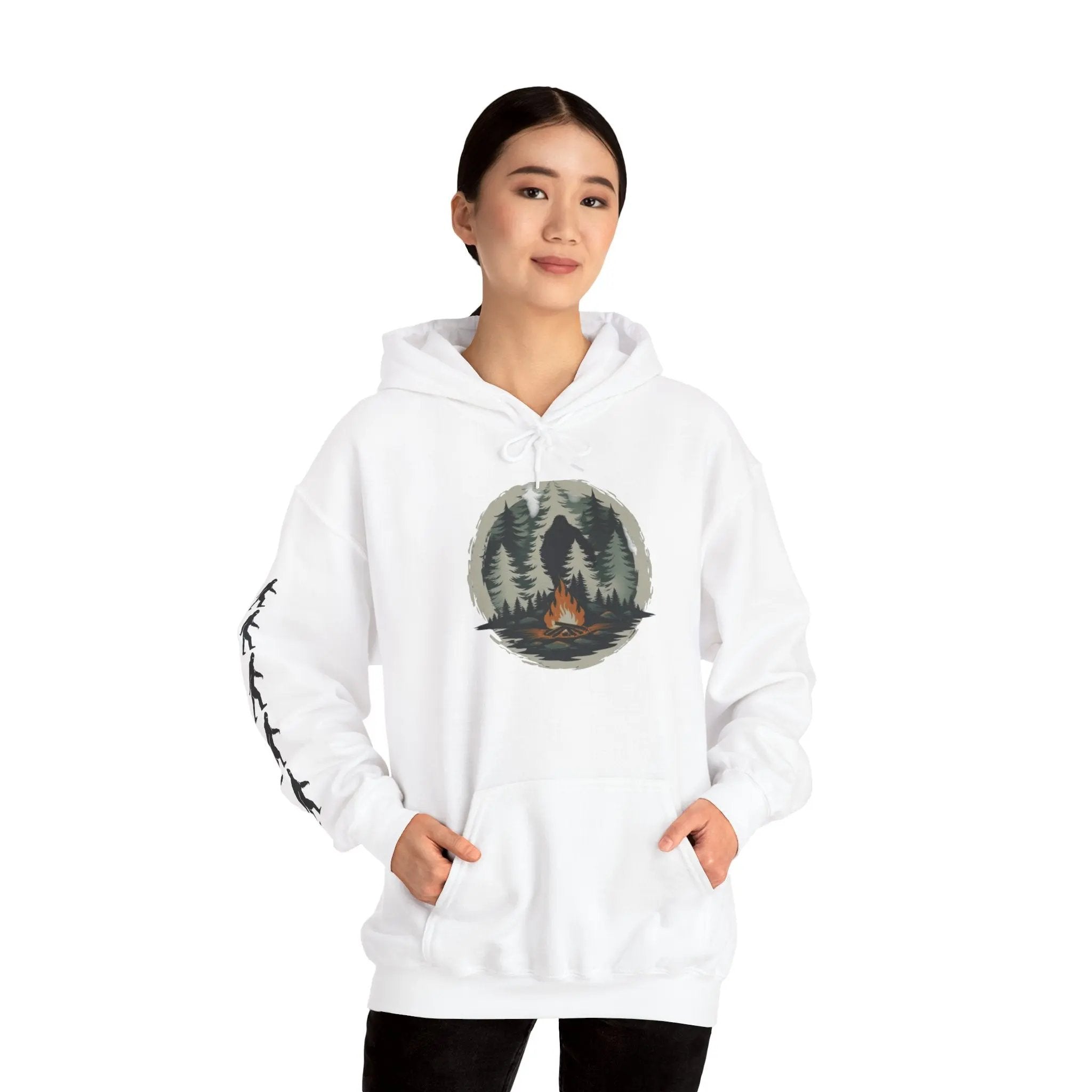 Person wearing a white hoodie with a nature graphic and black bigfoot silhouettes on the right sleeve on a white background on a white background