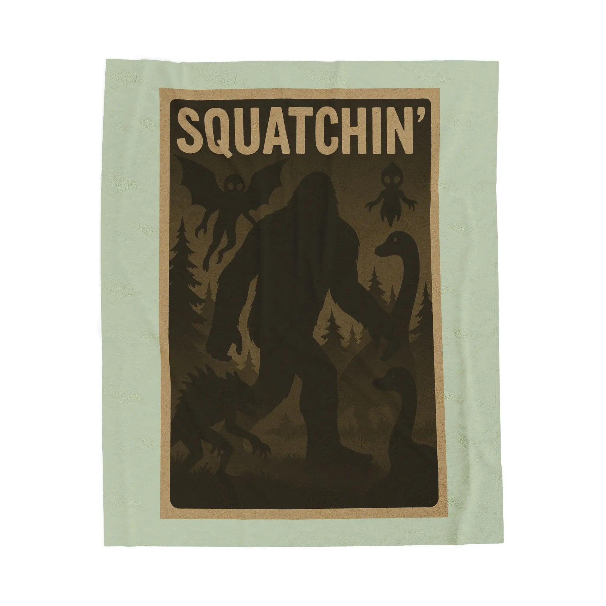 Light green fleece blanket with 'Squatchin' text across the top with silhouettes of bigfoot, loch Ness, werewolf, mothman, and an alien.