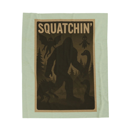 Light green fleece blanket with 'Squatchin' text across the top with silhouettes of bigfoot, loch Ness, werewolf, mothman, and an alien.