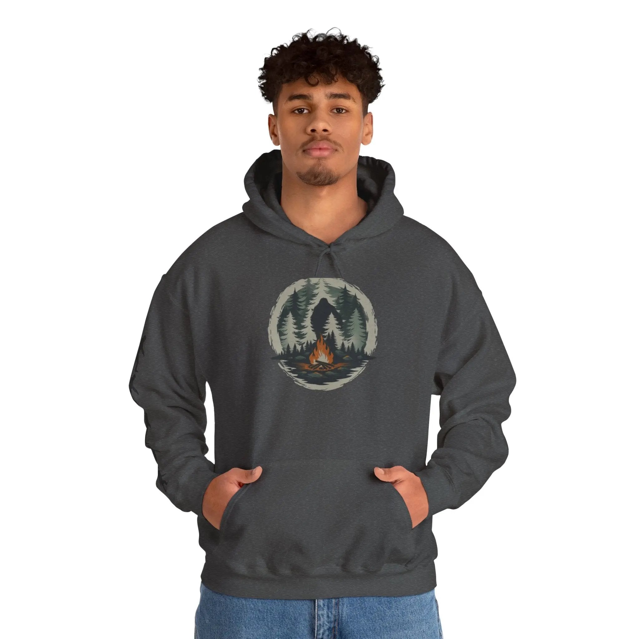 Person wearing a dark gray hoodie with a forest design and black bigfoot silhouettes on the right sleeve on a white background on a white background
