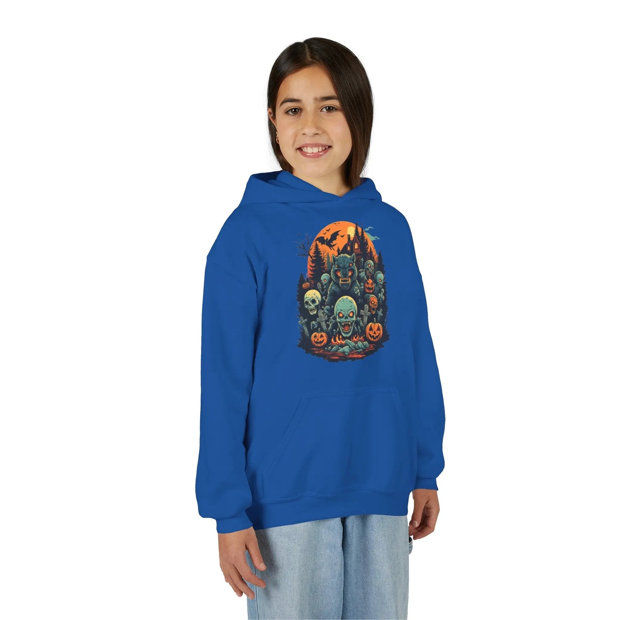 Older child wearing a blue hoodie with a colorful Halloween graphic design of werewolves, zombies, and other cryptids on a white background