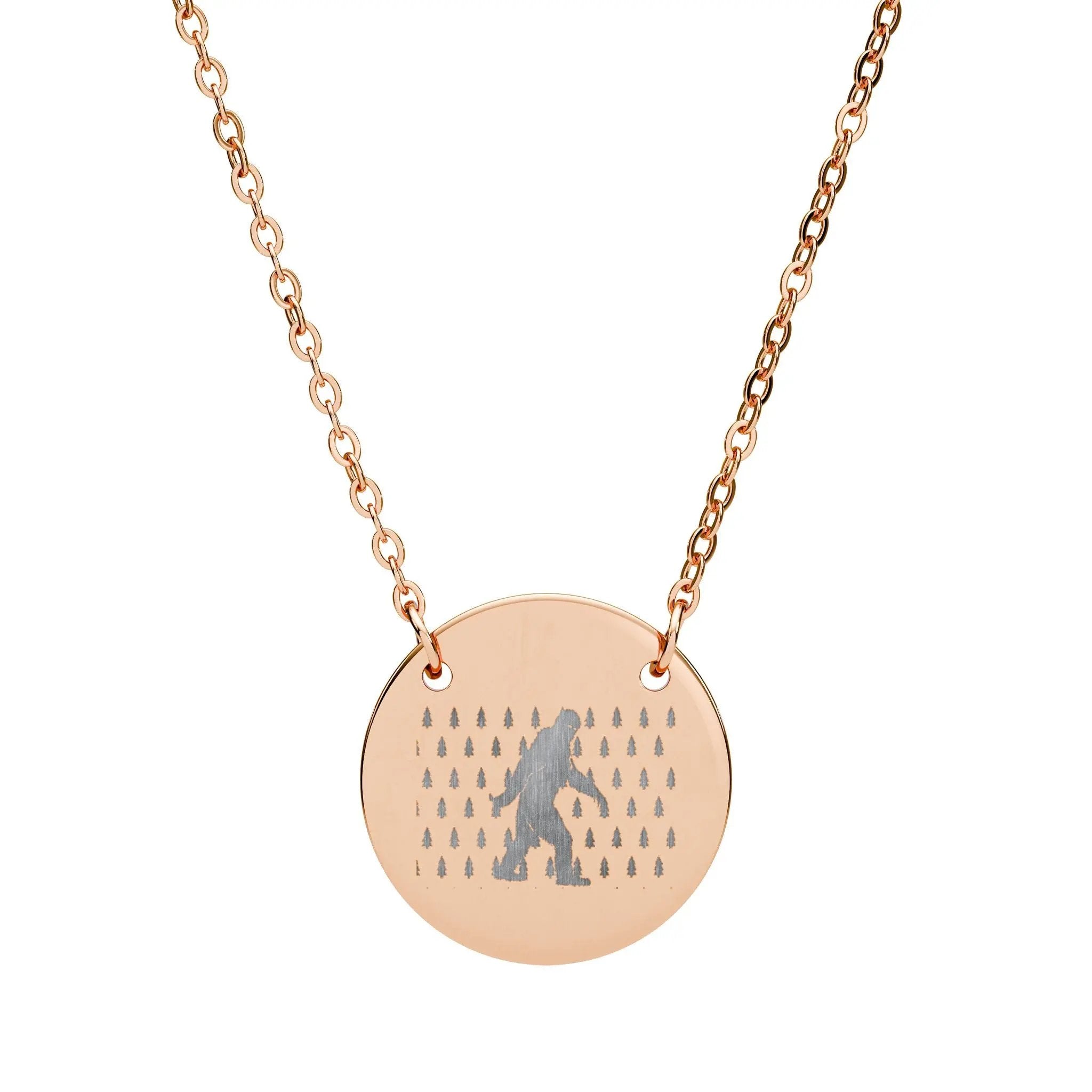 Rose gold necklace with a round pendant featuring a silhouette of bigfoot and trees on a white background