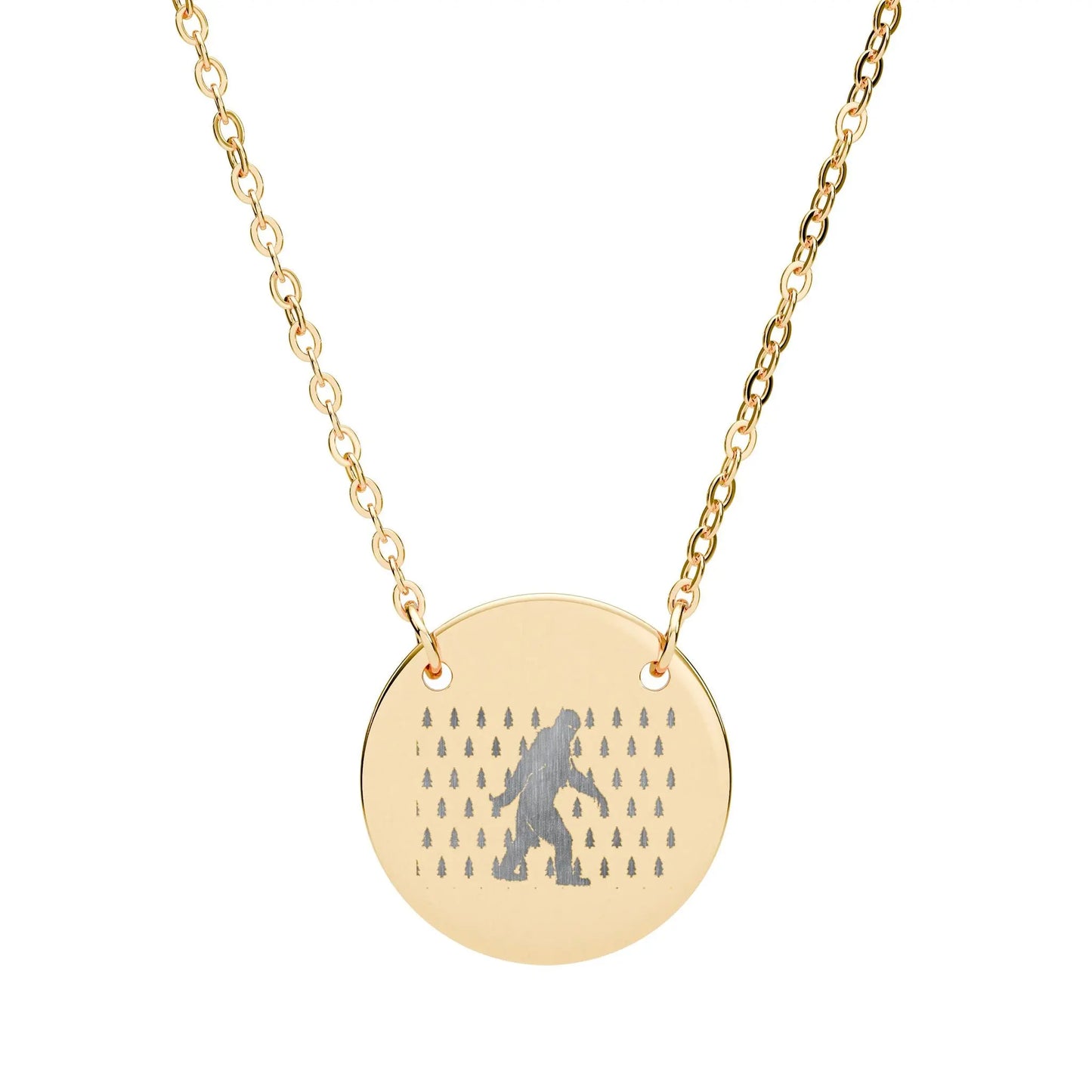Gold necklace with a round pendant featuring a silhouette of bigfoot and small trees on a white background