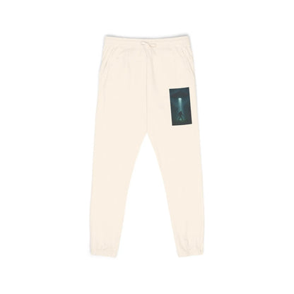 Beige sweatpants with a small graphic of a UFO with a beam of light on a bigfoot silhouette on the left leg on a white background