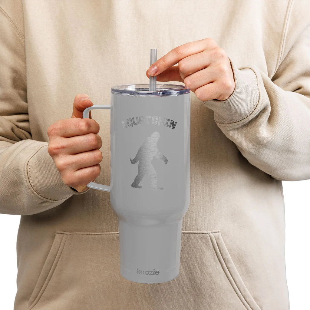 Person holding a gray tumbler with a straw, wearing a beige hoodie.