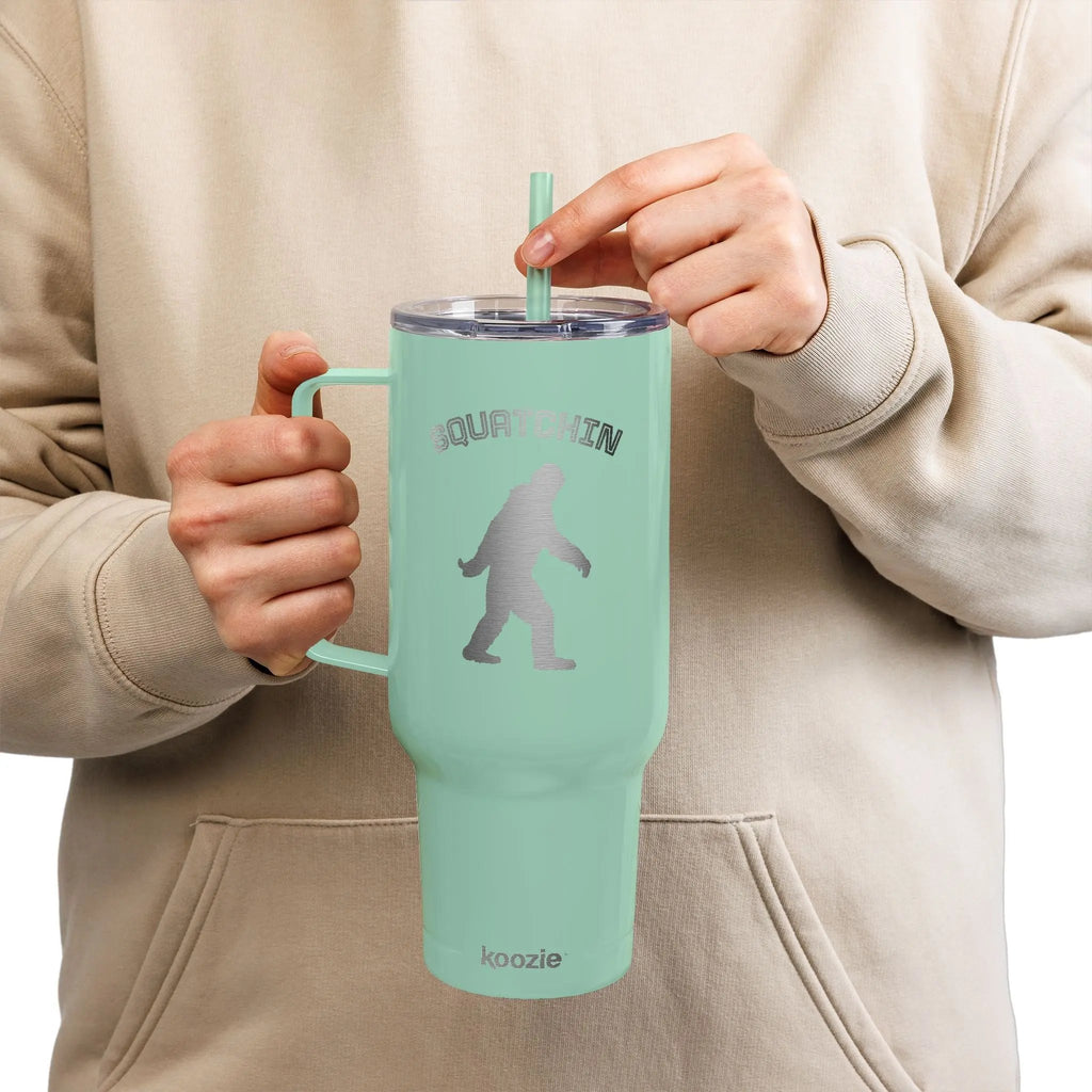 Person holding a mint green tumbler with a straw, wearing a beige hoodie.